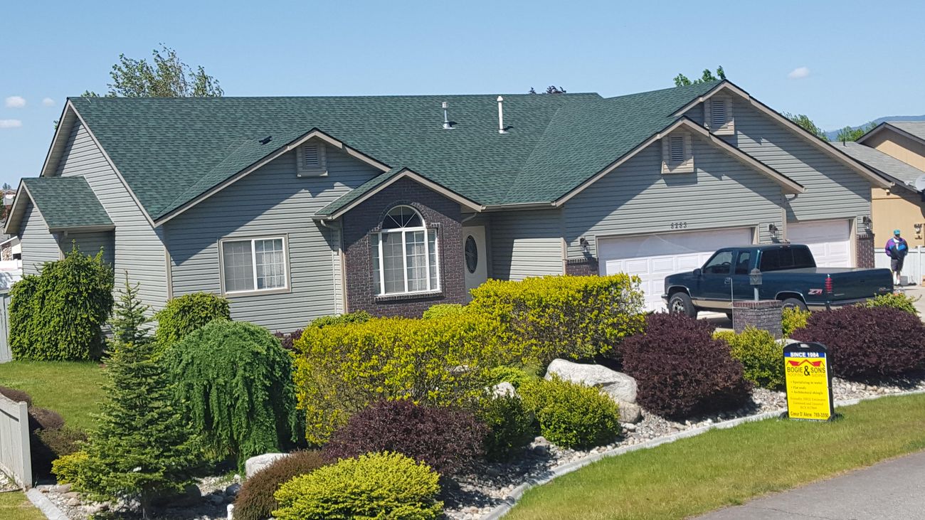 Coeur d'Alene home with lifetime warranty vinyl siding and a green architectural shingle roof, with a Bogie & Sons yard sign out front