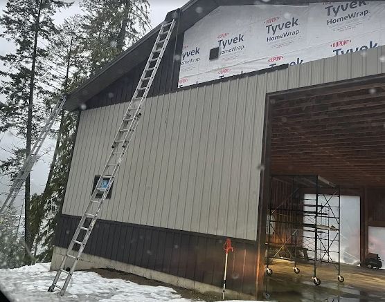 Metal siding going up over house wrap with a ladder in place